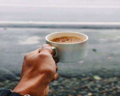 Indian person relaxing with a cup of tea in morning sunlight
